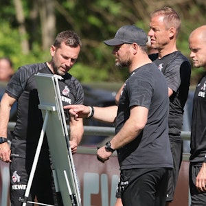 Steffen Baumgart steht mit seinen Assistenten André Pawlak, Kevin McKenna und René Wagner beim Training des 1. FC Köln vor einer Taktik-Tafel.