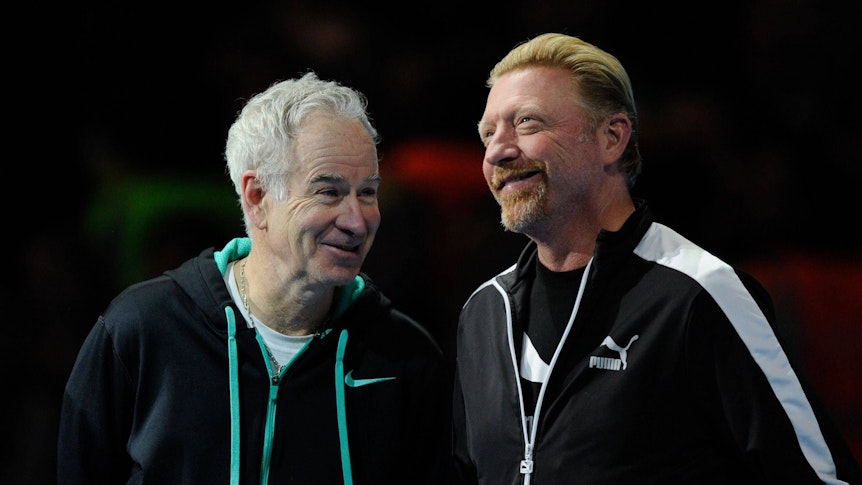 John McEnroe und Boris Becker stehen lachend nebeneinander.