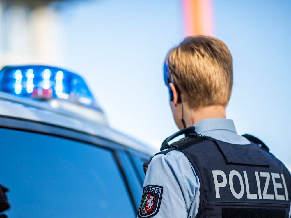 Eine Polizistin steht am 28. September 2021 vor einem Streifenwagen, dessen Blaulicht leuchtet.