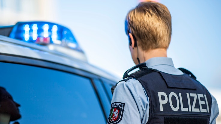Eine Polizistin steht am 28. September 2021 vor einem Streifenwagen, dessen Blaulicht leuchtet.