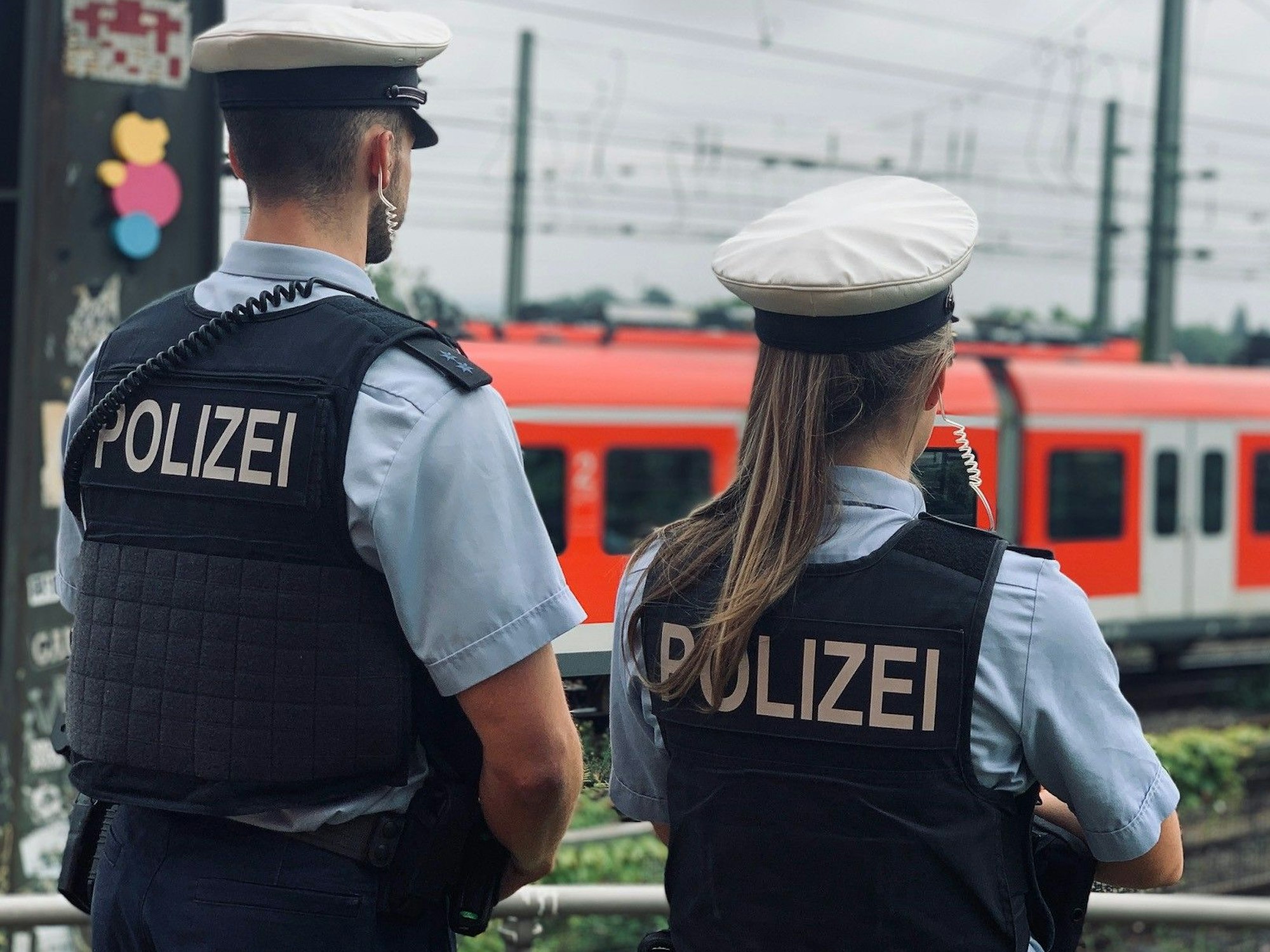 Das Foto zeigt eine Polizistin und einen Polizisten, die die Bahngleise beobachten.