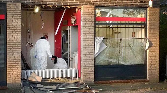 Eine Beamtin und ein Beamter in Schutzanzügen untersuchen den Tatort nach einer Geldautomatensprengung in NRW.
