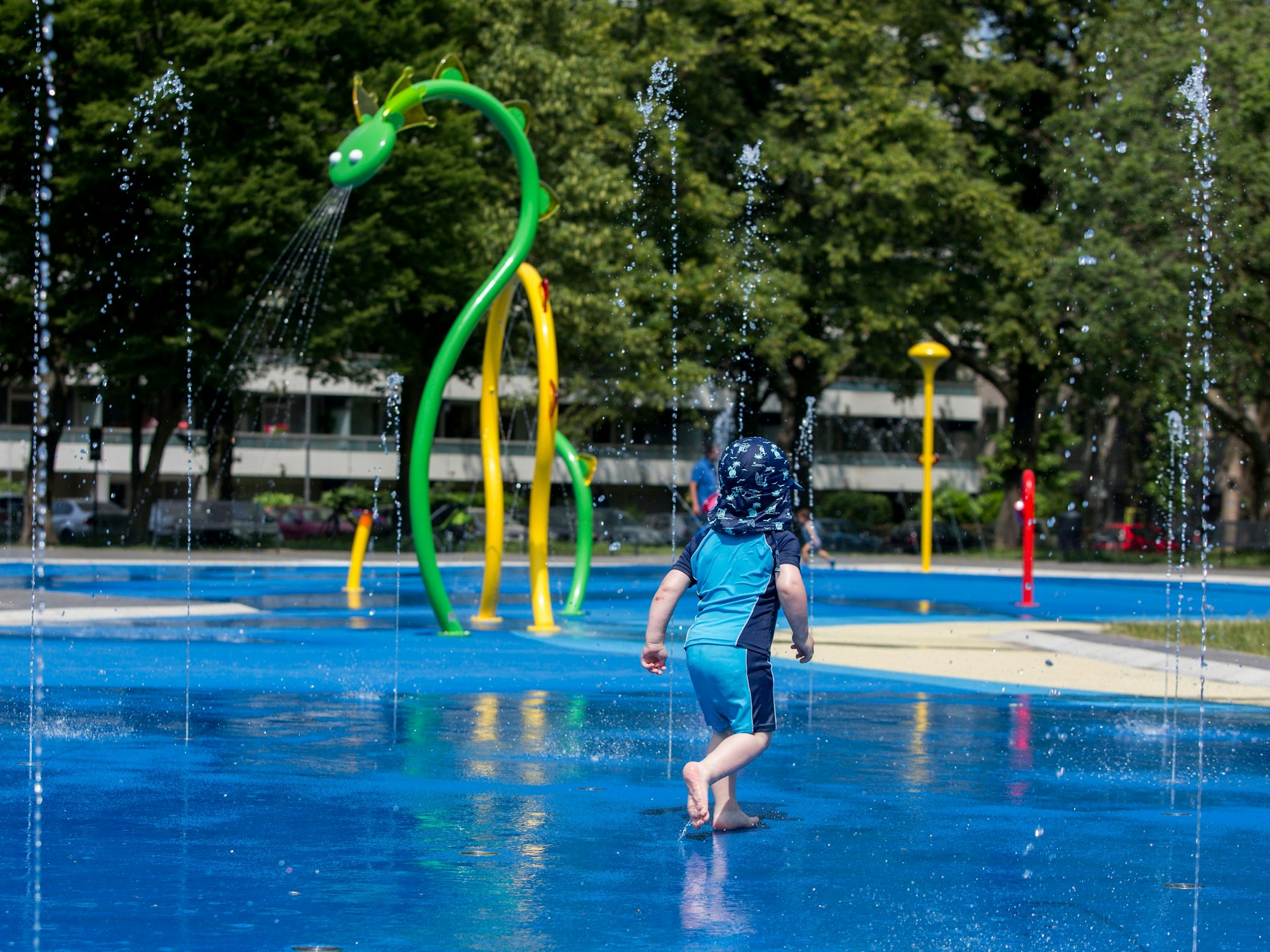Ein Kind läuft durch die Wasserfontänen auf dem Wasserspielplatz.