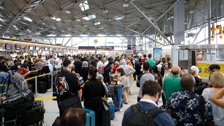 Reisende stehen am 24. Juni 2022 in einer Schlange von mehreren hundert Metern für die Sicherheitskontrolle am Flughafen Köln-Bonn an.