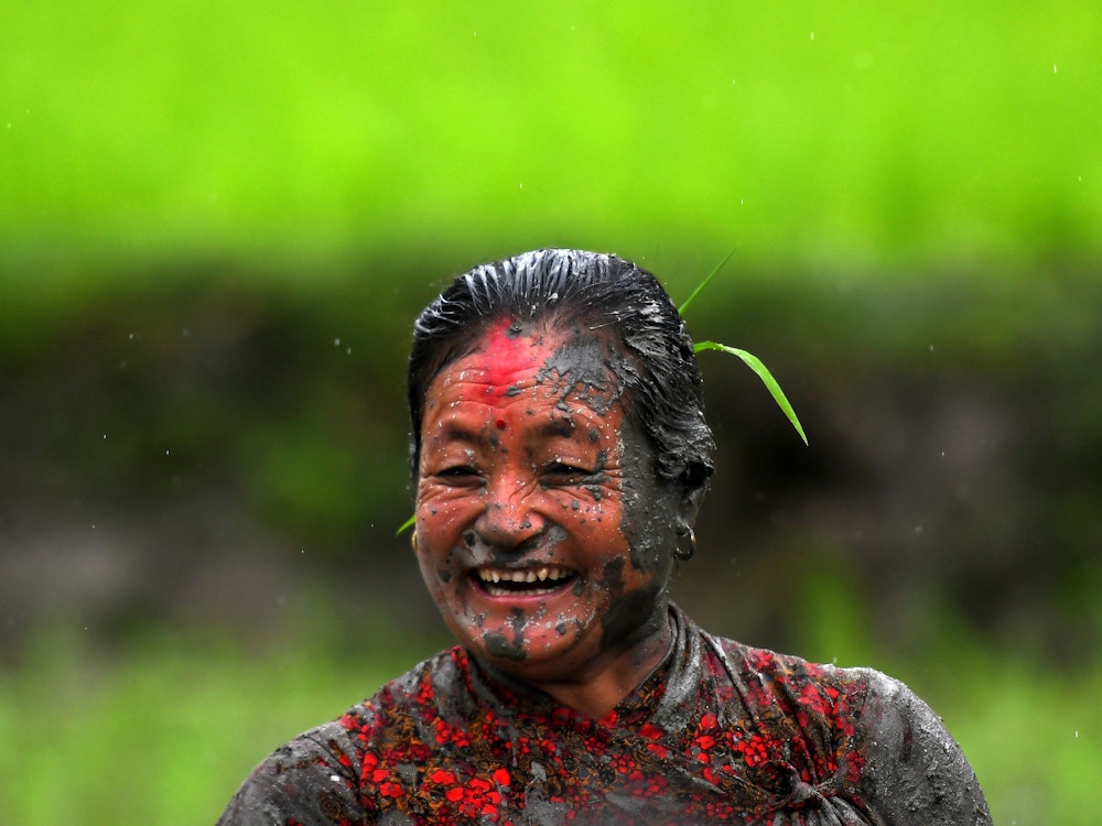 Ein von Schlamm bedeckter Farmer freut sich beim Beginn der Reispflanzsaison beim „National Paddy Day“ in Nepal