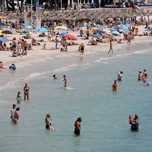 Menschen schwimmen und sonnen sich am Strand von Palmanova auf Mallorca.