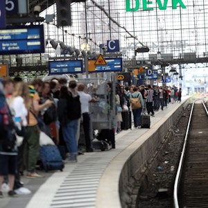 Menschen warten an Gleis 5 in Köln auf einen Zug.