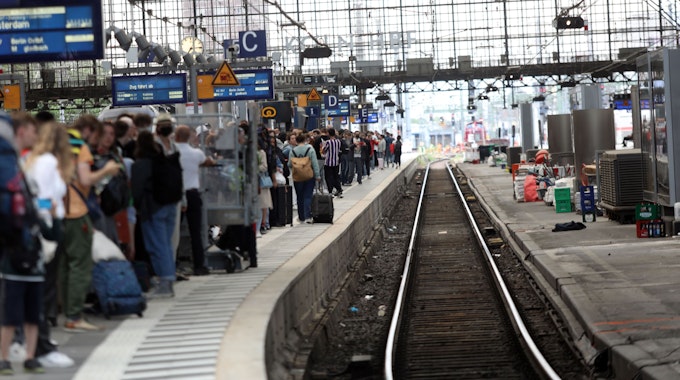 Menschen warten an Gleis 5 in Köln auf einen Zug.