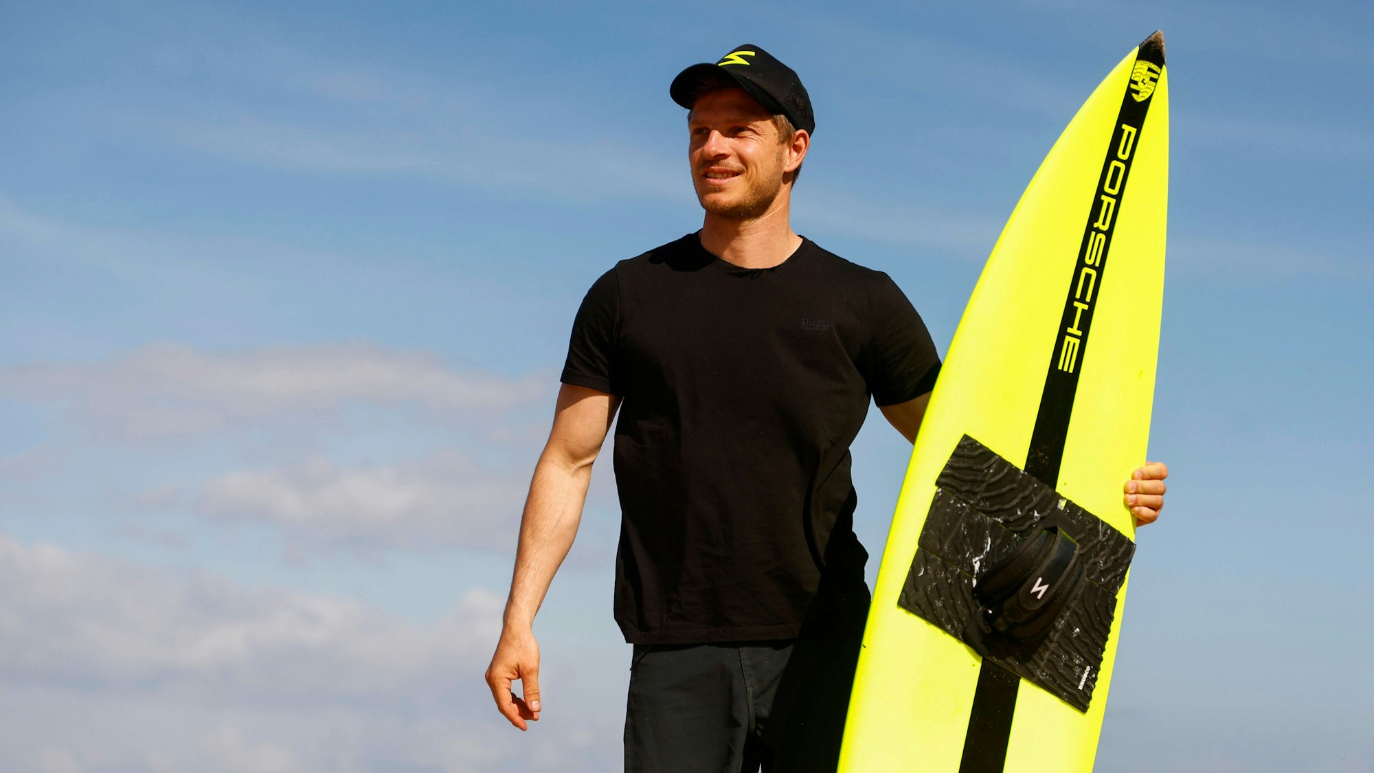 Sebastian Steudtner schaut in die Ferne – in der Hand sein Surfbrett.