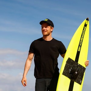 Sebastian Steudtner schaut in die Ferne – in der Hand sein Surfbrett.