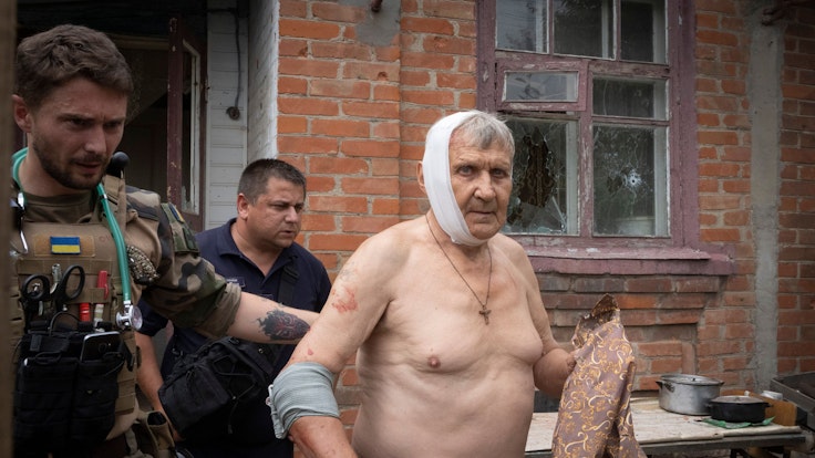 30.06.2022, Ukraine, Slowjansk: Ein Sanitäter hilft einem Mann, der durch russischen Beschuss verwundet wurde, sein Haus zu verlassen.