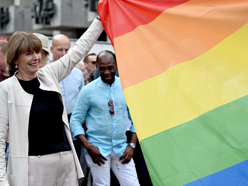 Henriette Reker, Kölner Oberbürgermeisterin, hilft beim Hissen einer Regenbogen-Flagge.