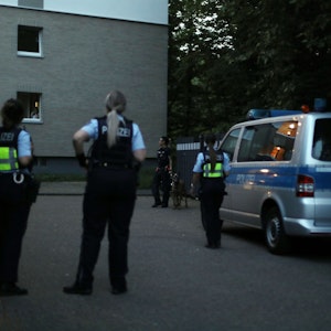 Polizisten und Polizistinnen stehen bei einem Großeinsatz vor einem Wohnhaus in Köln Ostheim.
