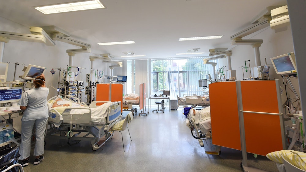 Auf der Intensivtherapie-Station (ITS) in einer Klinik in Sachsen steht eine Mitarbeiterin am Bett einer Patientin.