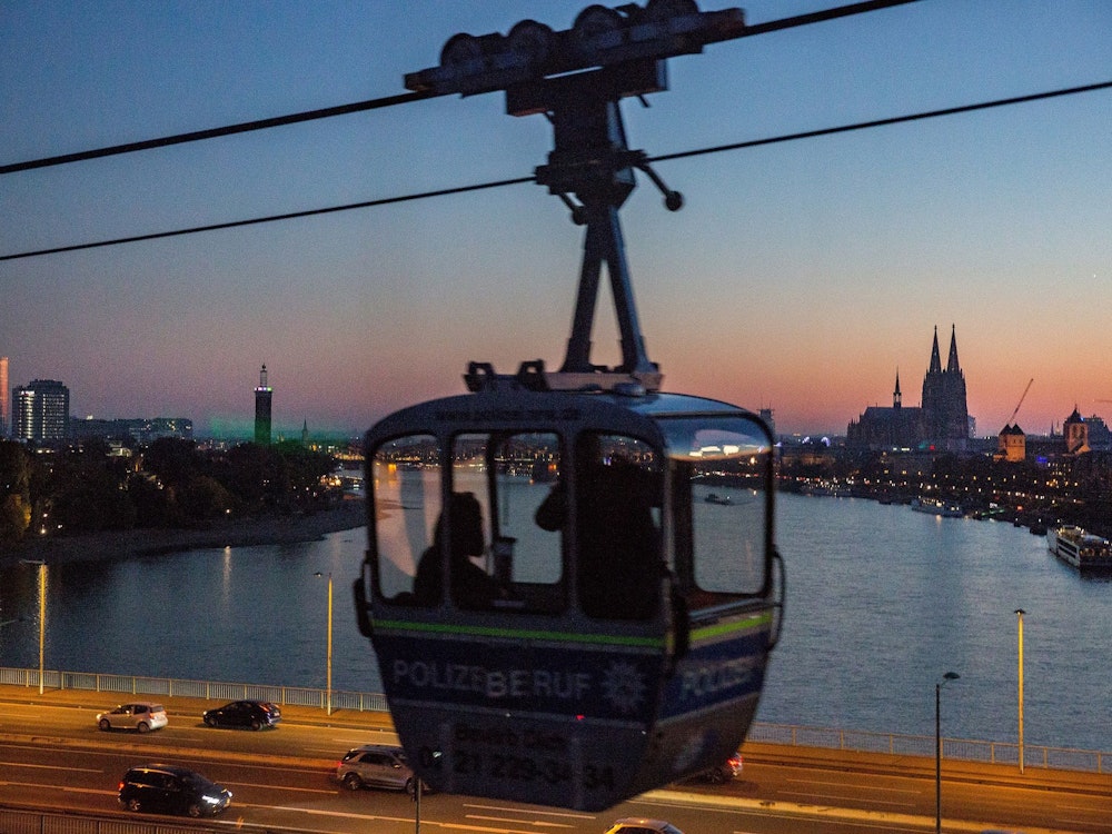 Eine Seilbahn-Gondel fährt über die Zoobrücke, man blickt auf den Rhein und den Kölner Dom.