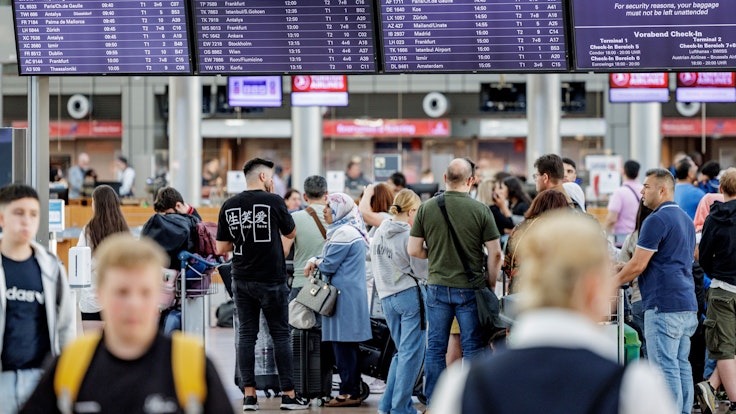 Fluggäste warten am 3. Juli 2022 im Helmut Schmidt Flughafen in Hamburg vor den Check-In Schaltern auf die Abfertigung. Zu Beginn der Sommerferien herrscht im Norden großer Andrang am Flughafen.