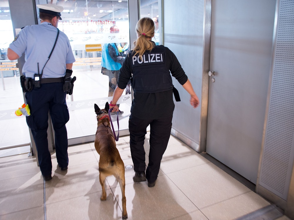 Polizisten mit einem Hund betreten 30. Mai 2016 den Sicherheitsbereich im Terminal 1 am Flughafen Köln/Bonn (Nordrhein-Westfalen).