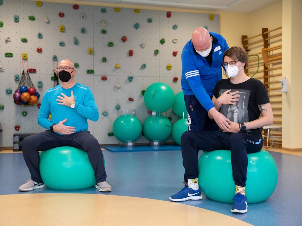 Die long-covid-Patienten Jörg Schneider (links) und Ulrich Lowers (rechts) machen ein Atemtraining mit Physiotherapeut Mirko Weernink in einem Gymnastikraum der Klinik Teutoburger Wald, eine Reha-Klinik für Post-Covid Erkrankte.