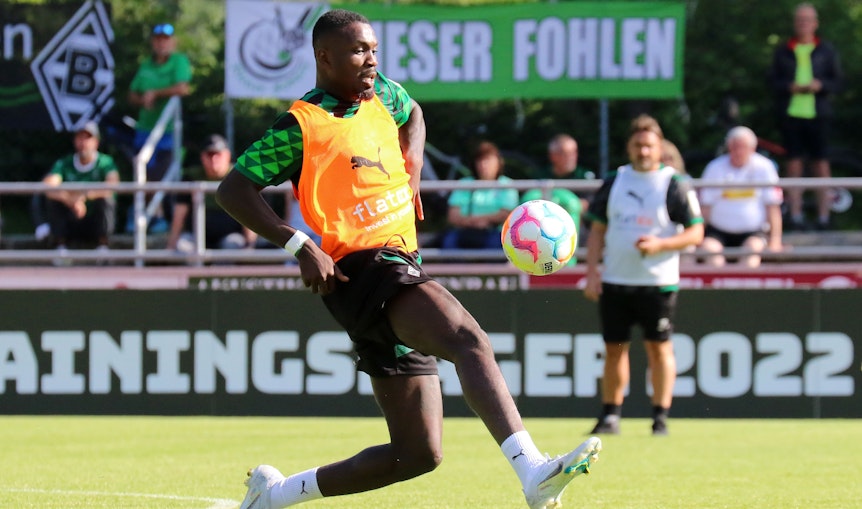 Marcus Thuram, hier am 5. Juli 2022 bei einer Einheit im Trainingslager, soll bei Borussia Mönchengladbach bleiben. Thuram nimmt den Ball mit dem rechten Fuß an, im Hintergrund wird er von Trainer Daniel Farke beobachtet.