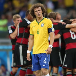 Brasiliens David Luiz schaut geknickt, im Hintergrund jubeln die deutschen Spieler.