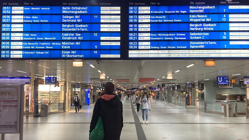 Ein Mann schaut im Hauptbahnhof in Düsseldorf auf eine große Anzeigetafel.