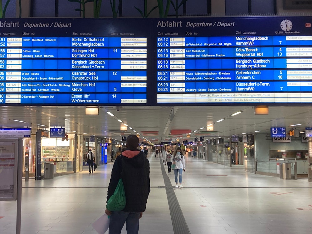 Eine Frau schaut im Hauptbahnhof in Düsseldorf auf eine große Anzeigetafel.
