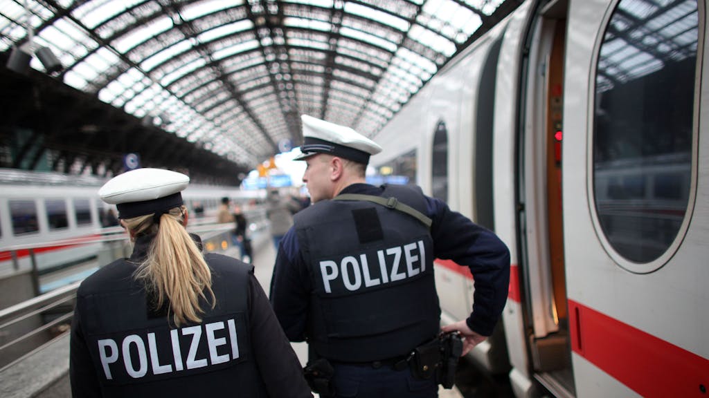 Eine Bundespolizistin und ein Bundespolizist patrouillieren auf einem Bahnsteig des Kölner Hauptbahnhofs, an dem ein ICE gehalten hat.