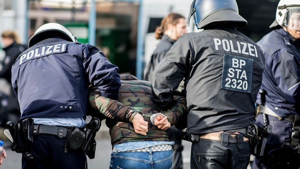 Ein Demonstrant wird von Polizisten am Düsseldorfer Flughafen festgenommen. 