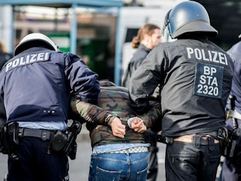 Ein Demonstrant wird von Polizisten am Düsseldorfer Flughafen festgenommen. 