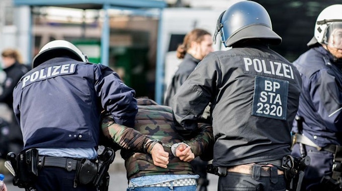 Ein Demonstrant wird von Polizisten am Düsseldorfer Flughafen festgenommen.