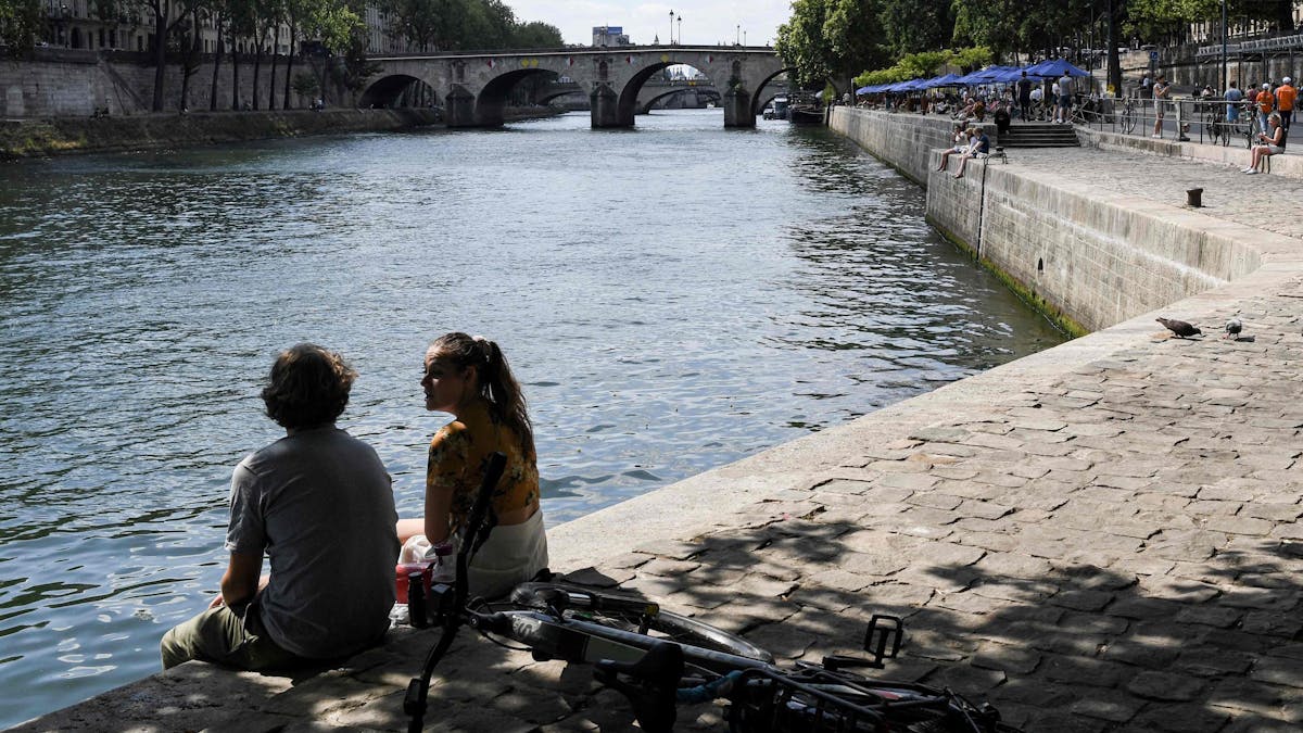 Ein Paar sitzt an dem Ufer der Seine. Entlang der Seine in Paris lockt der über den Sommer eingerichtete Stadtstrand seit Samstag wieder mit Freizeit- und Kulturaktivitäten.