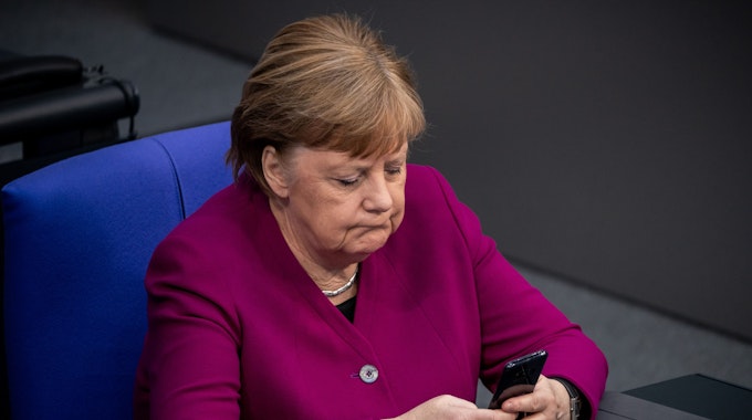 Dieses Foto aus dem Jahr 2020 zeigt die damalige Bundeskanzlerin Angela Merkel, wie sie ihr Handy im Bundestag benutzt.
