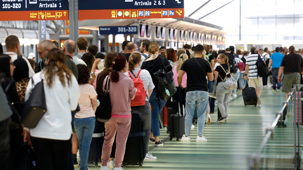 Passagiere stehen in einer Schlange von mehreren hundert Metern für die Sicherheitskontrolle am Flughafen Köln-Bonn an.