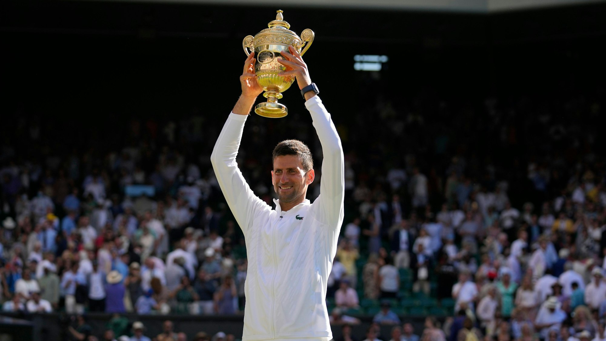 Novak Djokovic hält die Wimbledon-Trophäe über seinem Kopf.