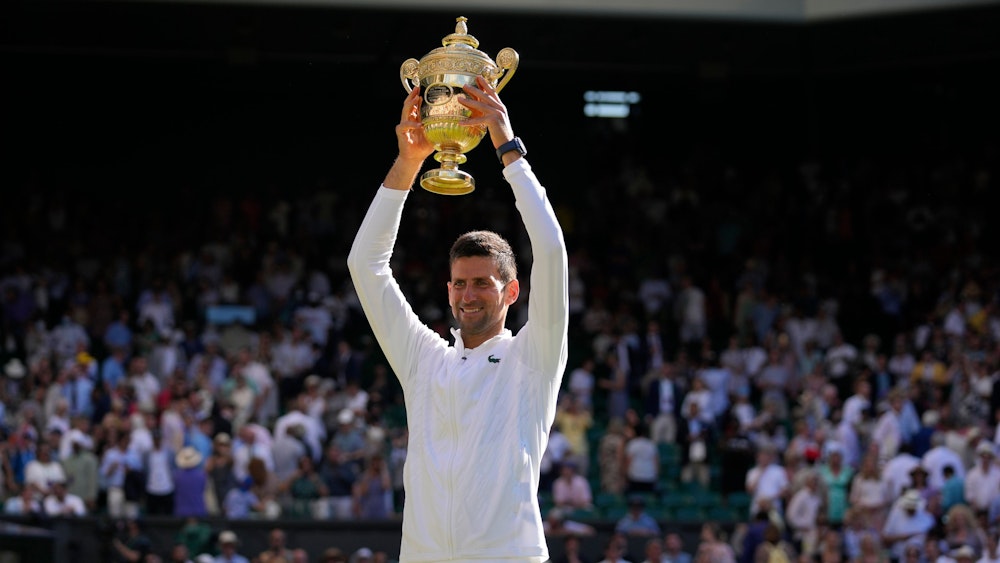 Novak Djokovic hält die Wimbledon-Trophäe über seinem Kopf.