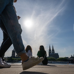Am Rheinboulevard flanieren junge Leute durch den Sonnenschein.