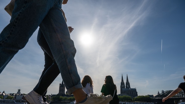 Am Rheinboulevard flanieren junge Leute durch den Sonnenschein.