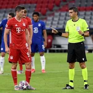 Bayern Münchens Robert Lewandowski steht neben Schiedsrichter Ovidiu Hațegan aus Rumänien vor seinem Elfmeter.