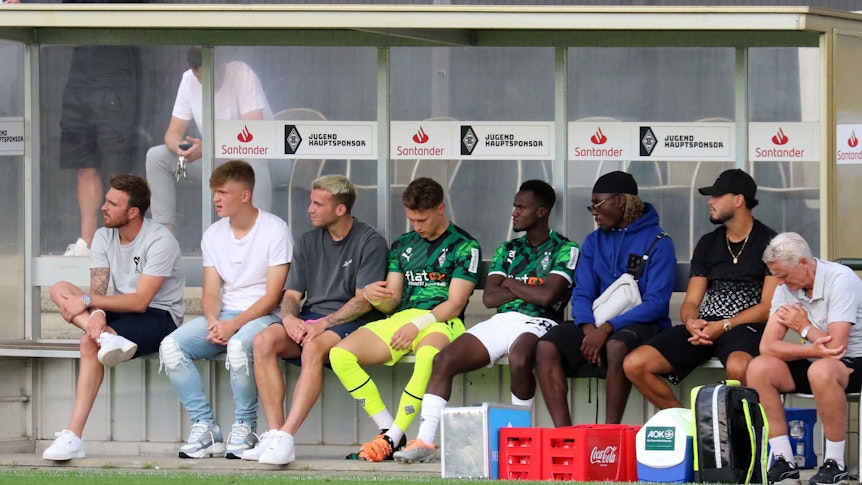 Prominent besetzte Zuschauerbank, mit unter anderem Ramy Bensebaini (2. v. r.) und Luca Netz (2. v. l.) im Rahmen des Testspiels zwischen Borussia Mönchengladbach und Viktoria Köln am 13. Juli 2022.