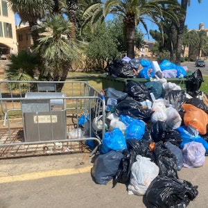 Sich stapelnde Müllsäcke vor einer überfüllten Mülltonne in Port d'Alcúdia auf Mallorca am 14. Juli 2022.