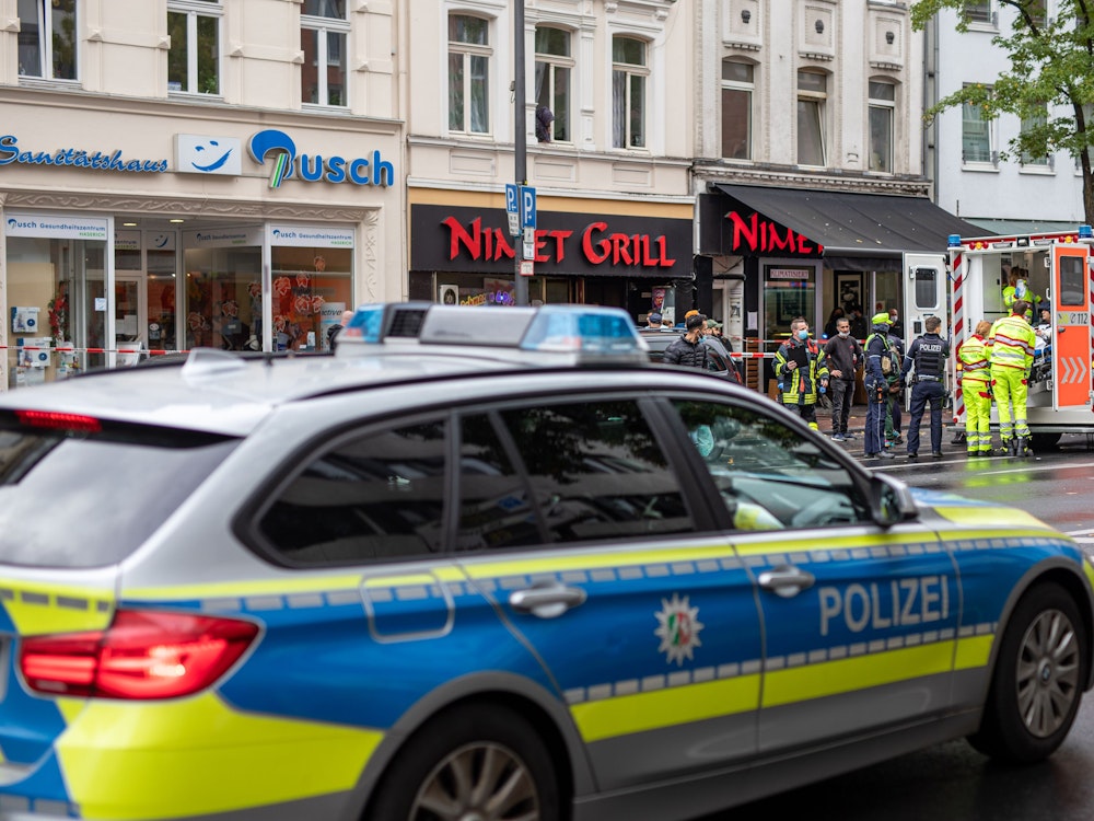 Einsatzkräfte stehen bei einem Polizeieinsatz vor einem Fast-Food -Laden auf der Kalker Hauptstraße, während ein Verletzter in einem Rettungswagen (RTW) behandelt wird.