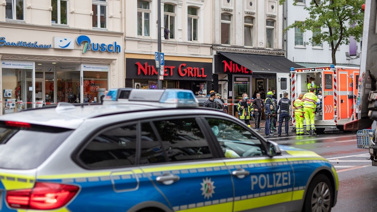 Einsatzkräfte stehen bei einem Polizeieinsatz vor einem Fast-Food -Laden auf der Kalker Hauptstraße, während ein Verletzter in einem Rettungswagen (RTW) behandelt wird.