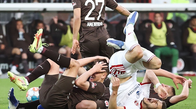 Spieler vom FC St. Pauli und vom 1. FC Nürnberg liegen nach einem Zusammenstoß auf dem Rasen.