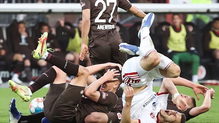 Spieler vom FC St. Pauli und vom 1. FC Nürnberg liegen nach einem Zusammenstoß auf dem Rasen.