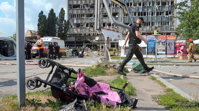 Ein mit Blut verschmierter Kinderwagen, im Hintergrund ein durch russische Bomben zerstörtes Haus. Hätte der ukrainische Präsident das wirklich verhindern können, fragt unsere Kollegin.