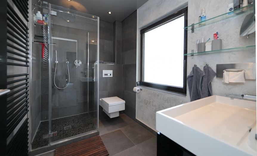 Das Badezimmer ist modern ausgestattet und verfügt über eine Regendusche.