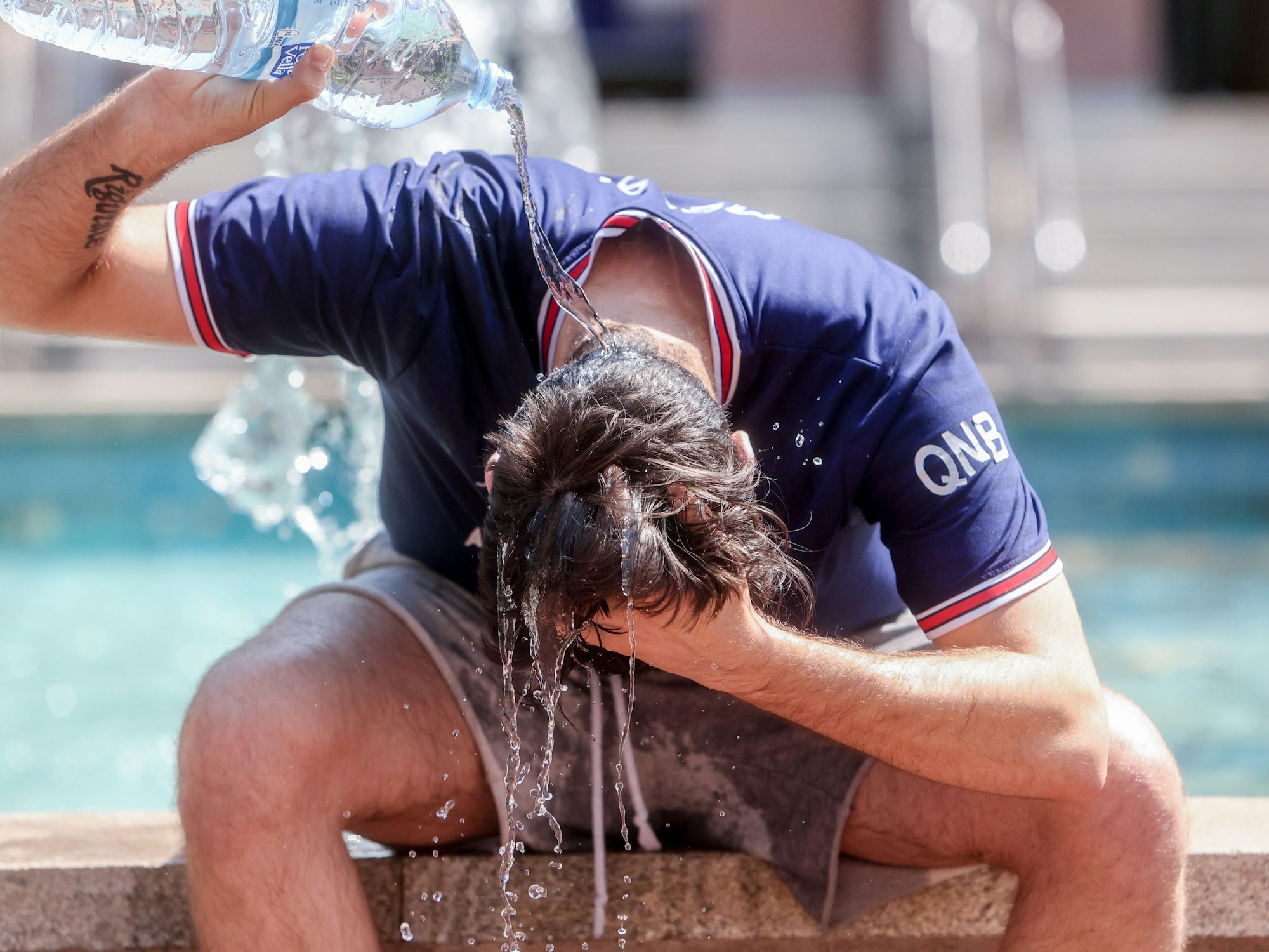 Ein junger Mann übergießt sich mit einer Wasserflasche, um die Hitze zu bekämpfen. Dieses Foto stammt aus Spanien.