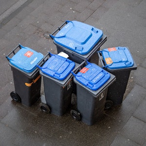 Abfalltonnen mit blauem Deckel, umgangssprachlich auch „Blaue Tonne“ genannt, für Altpapier stehen zur Abholung der AWB (Kölner Abfallwirtschaftsbetriebe) am Straßenrand.