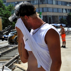 Ein Straßenarbeiter wischt sich am Montag (12.07.2010) in der Grillparzerstraße im Stadtteil Haidhausen in München (Oberbayern) bei großer Hitze den Schweiß ab.