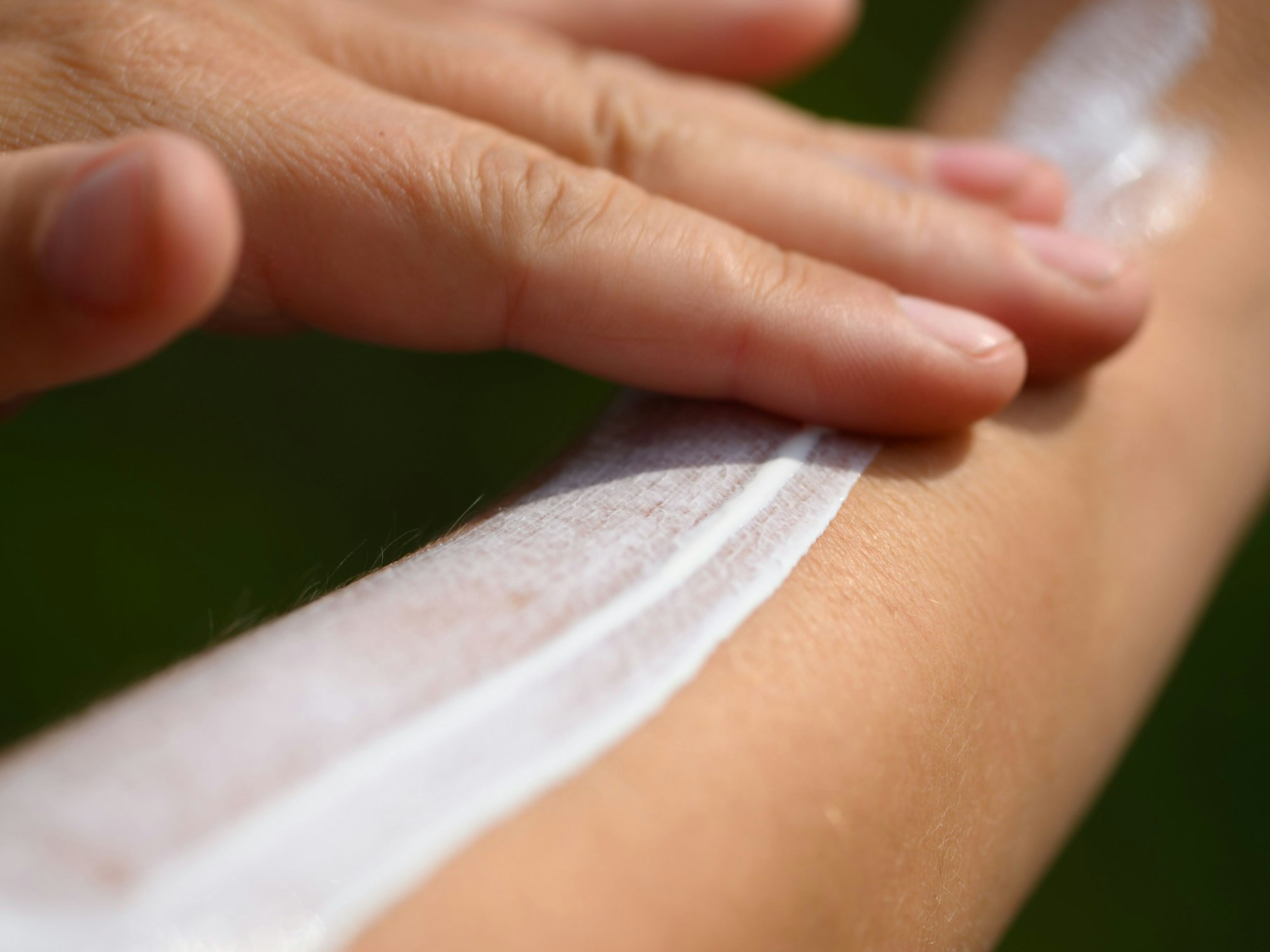 Eine Frau schmiert sich ihren Unterarm mit Sonnencreme ein.